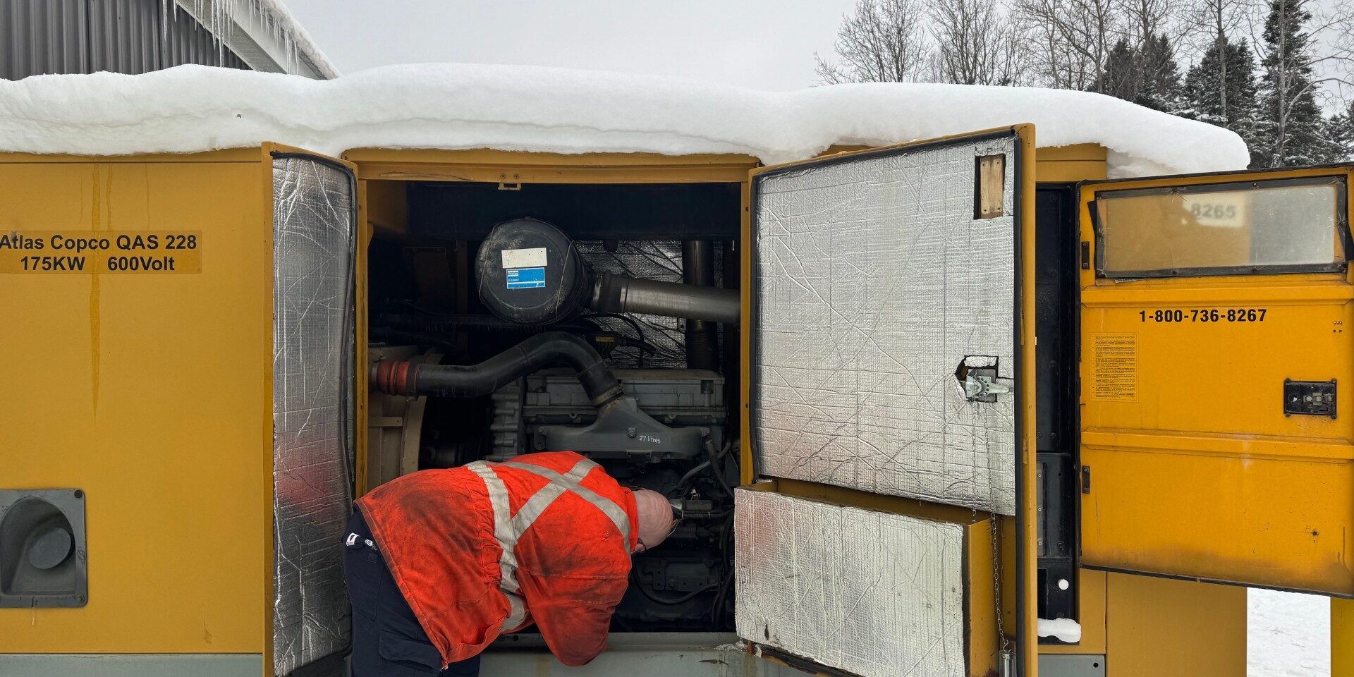 Heavy equipment mechanic working in the yard on a generator.